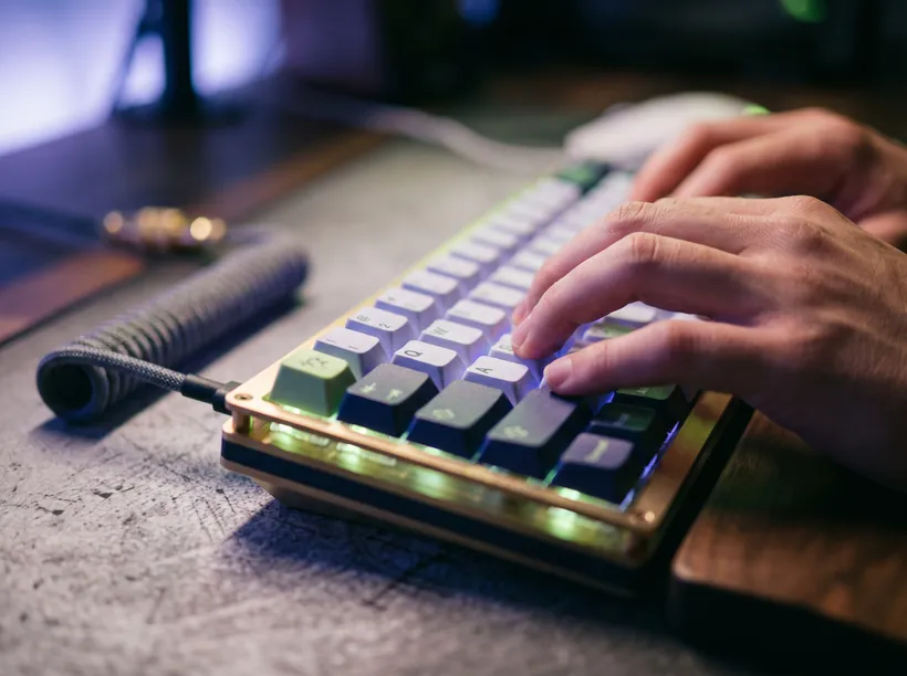 Hands typing on a keyboard with ambient indigo lighting